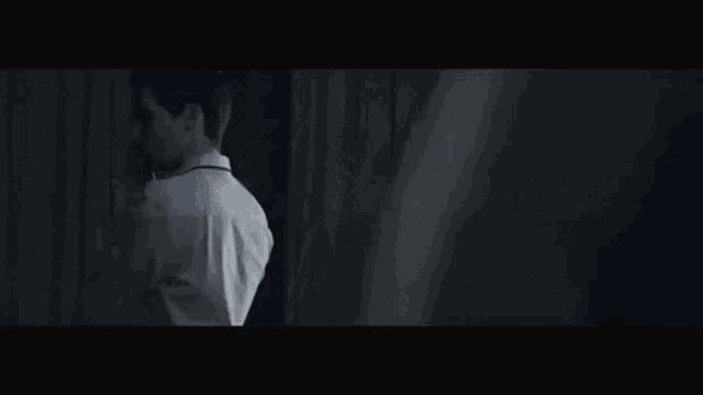 a man in a white shirt is standing in a dark room with the words desire is everywhere on the screen behind him .