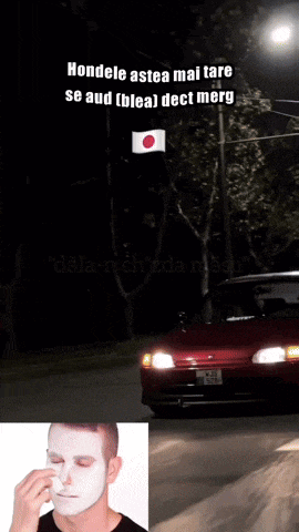 a man wipes his nose in front of a red car and a japanese flag
