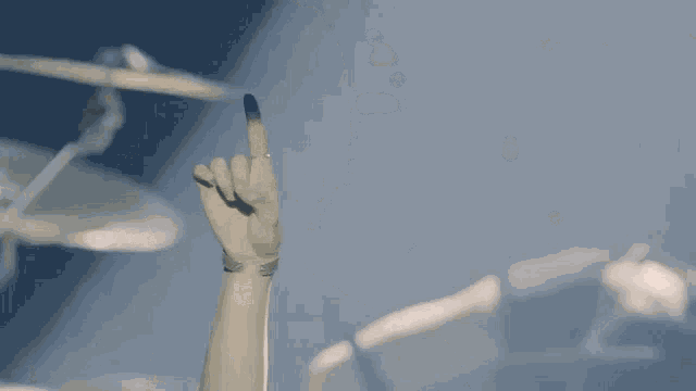 a young man in a white shirt is holding up his arm in the air .