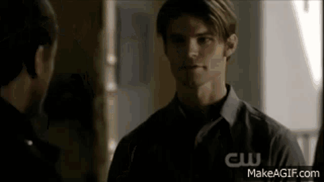a man in a black shirt is talking to another man in a room .