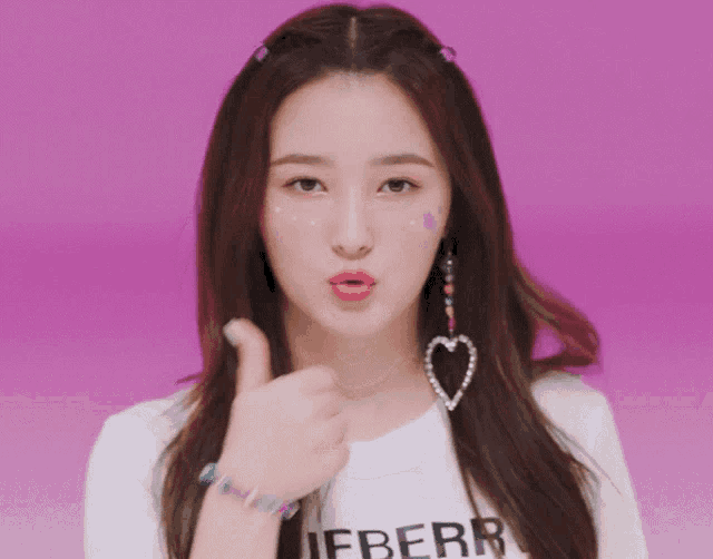 a girl with a heart shaped earring and a shirt that says lieberr gives a thumbs up