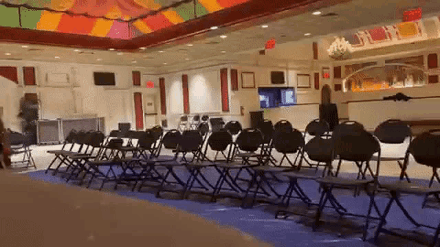 rows of folding chairs are lined up in a room with a red exit sign