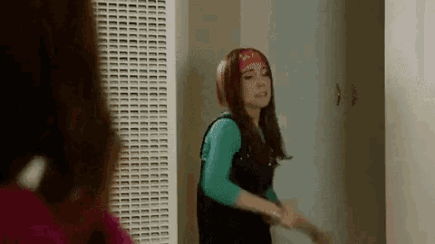 a woman wearing a bandana and a headband is standing in a room holding a brush .