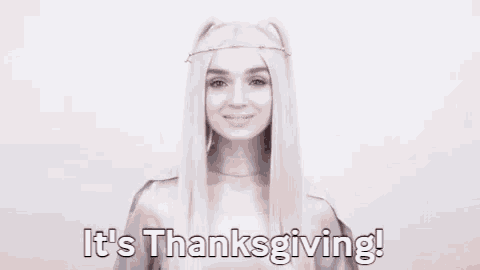 a woman with long white hair is smiling and says `` it 's thanksgiving ! ''
