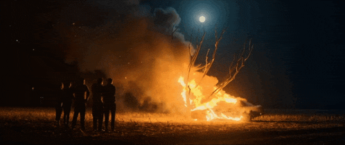 a group of people standing in front of a fire