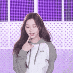 a woman in a hoodie is making a funny face with her finger on her lips .