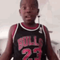 a young boy wearing a chicago bulls jersey is standing in a room .
