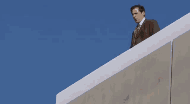 a man in a suit and tie is standing on a ledge with the words dwight you ignorant slut below him