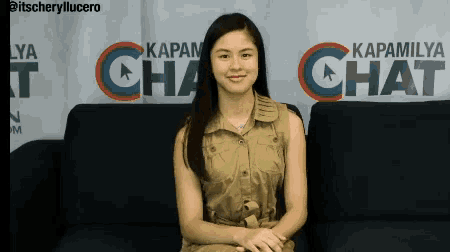 a woman sits on a couch in front of a sign that says ' kapam chat '