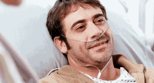 a man is laying in a hospital bed with an oxygen tube in his mouth .