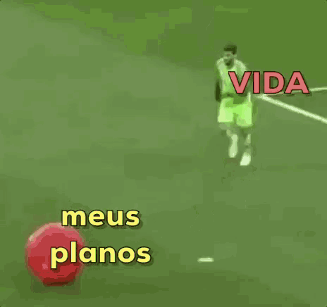 a soccer player is kicking a red ball on a field with the words vida meus planos on the bottom