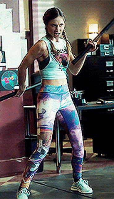 a woman in a crop top and colorful pants is holding a barbell