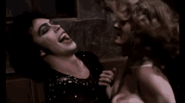 a man with his tongue out is licking another man 's face .