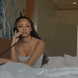 a woman is laying in bed talking on a telephone