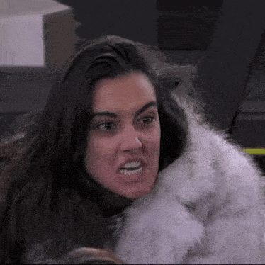 a woman is wearing a fur coat and making a funny face .