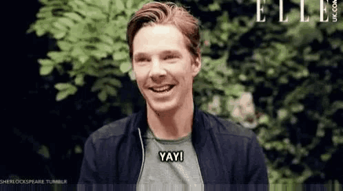 a man is smiling and saying yay in front of trees .