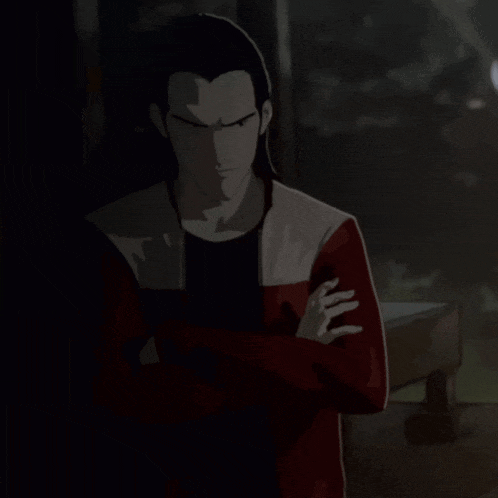 a man in a red and white jacket stands in the dark with his arms crossed