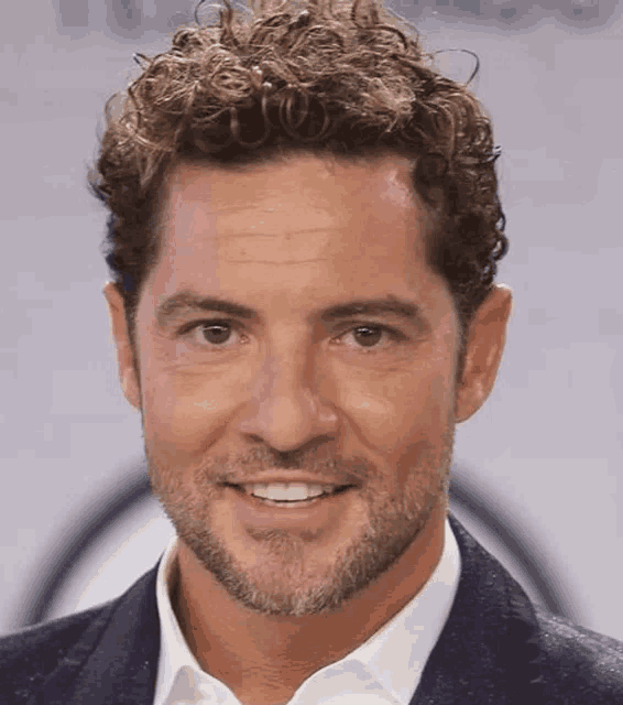 a man with curly hair and a beard smiles