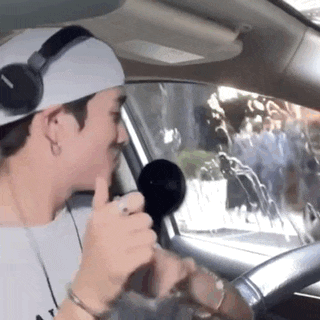 a man wearing headphones is singing into a microphone in a car .