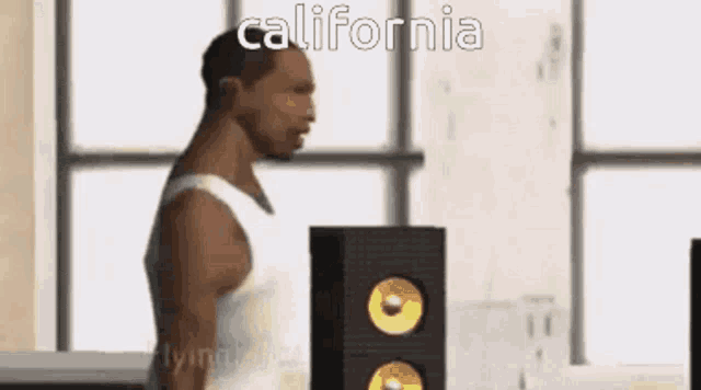 a man in a white tank top is standing in front of a wall with the words california written on it .