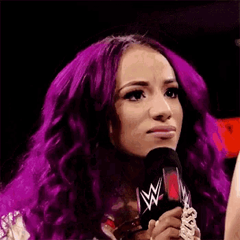 a woman with purple hair is holding a microphone .