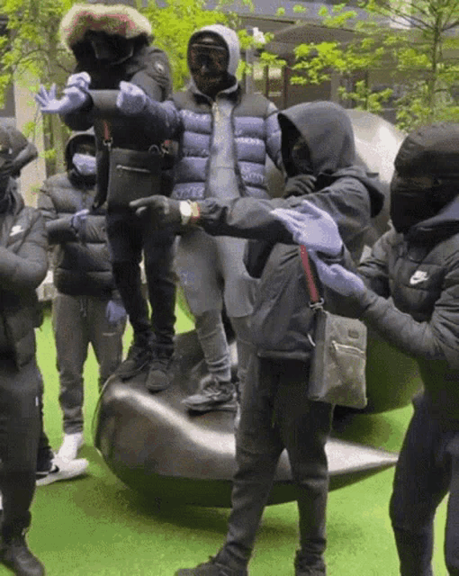 a group of people wearing masks are standing around a sculpture