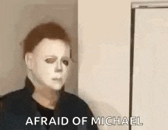 a person wearing a michael myers mask is standing next to a door and says `` afraid of michael '' .