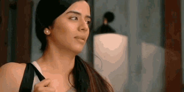 a woman is standing in front of a mirror and looking at herself in a mirror .