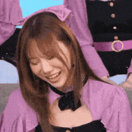 a woman wearing a purple shirt and a black bow tie is smiling