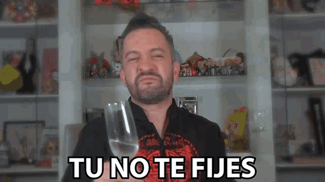 a man holding a glass of water with the words tu no te fijes above him