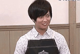 a man wearing an apron and a white shirt is smiling in a room .
