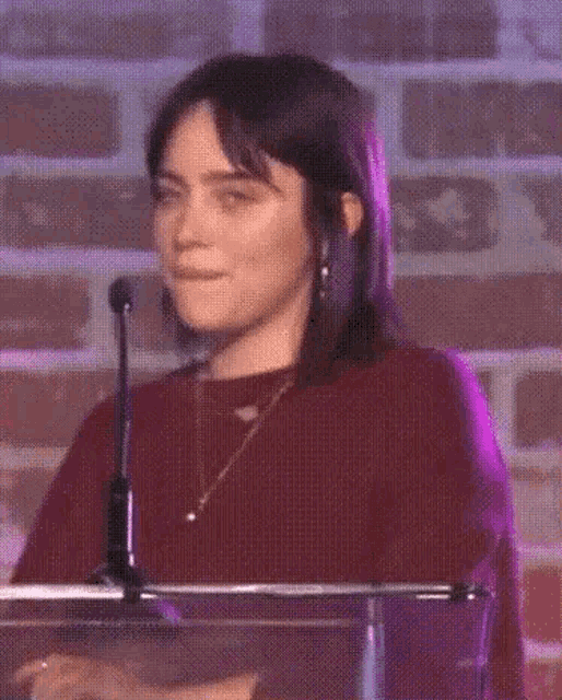 a woman is standing at a podium with a microphone and smiling .