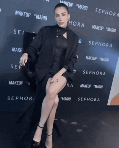 a woman is sitting in front of a wall that says sephora