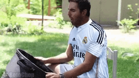a man wearing a fly emirates shirt is holding a pan