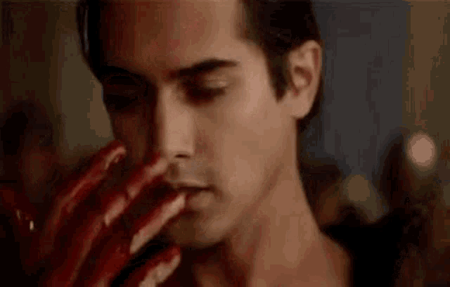a close up of a man with blood on his face and hands .