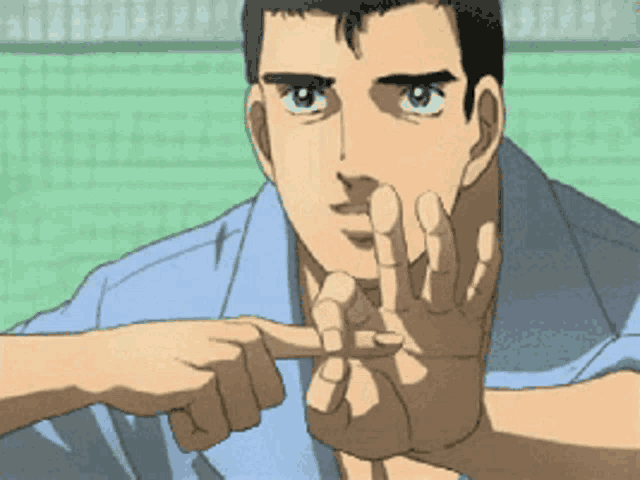 a man in a blue shirt is making a stop sign with his fingers