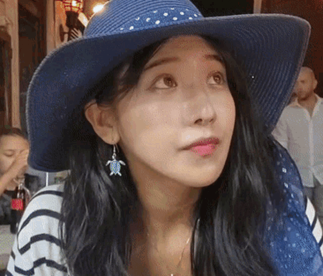 a woman wearing a blue hat and blue earrings
