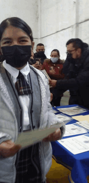 a girl wearing a mask holds a piece of paper in her hand