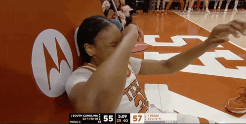 a texas basketball player wipes her face during a game against south carolina
