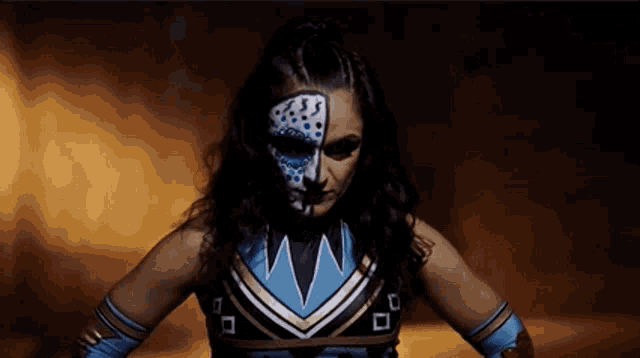 a woman with face paint on her face is wearing a blue and gold outfit .