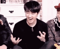a man in a black sweater is laughing while sitting next to another man .