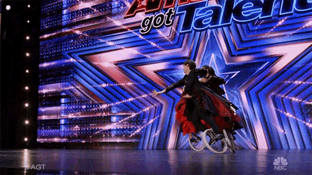 a man in a wheelchair dances with a woman in a red dress in front of a screen that says got talent on it