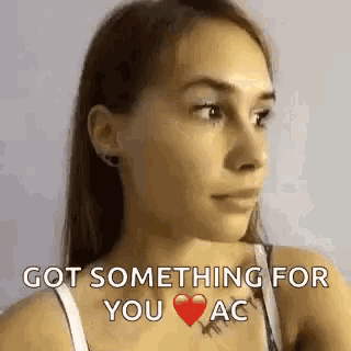 a woman in a white bra is looking at the camera with a heart on her chest and says `` got something for you ac '' .