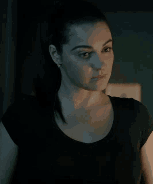 a woman wearing a black shirt and earrings looks to the side