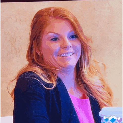 a woman with red hair is smiling in front of a cup that says imgplay on the bottom