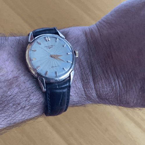 a man is wearing a longines watch with a black band