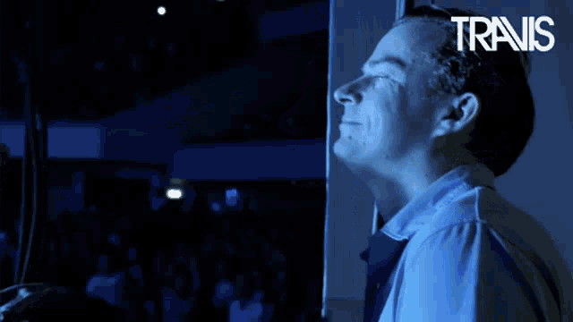 a man is playing a guitar in front of a crowd and the word travis is on the bottom