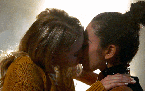 two women kissing with one wearing a choker