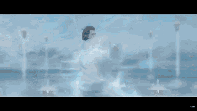 a person in a white dress is dancing in a room with a blue background .