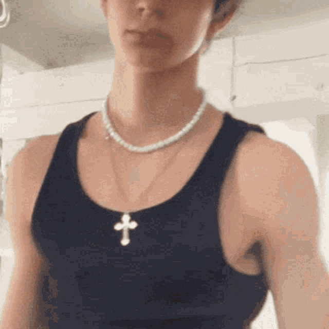 a man wearing a black tank top and a necklace with a cross on it